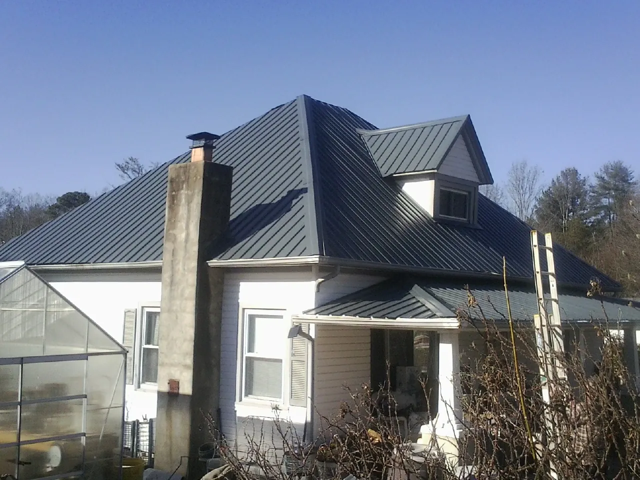 Dark blue standing seam metal roof on a white farmhouse with dormer — Slate & Tile Roof Repair by Roofing Brothers in Crumpler