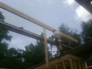 Carpenter setting a ridge beam over a new addition frame — Ice Dam Removal by Roofing Brothers in Crumpler