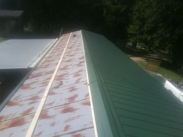 Old rusted panels beside newly installed green metal roofing — Wind Damage Roof Repair by Roofing Brothers in Crumpler