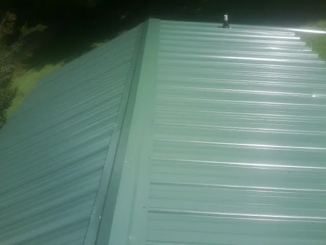 New green metal panels meeting at the ridge of a roof — Flat Roof Repair work by our crew in Crumpler