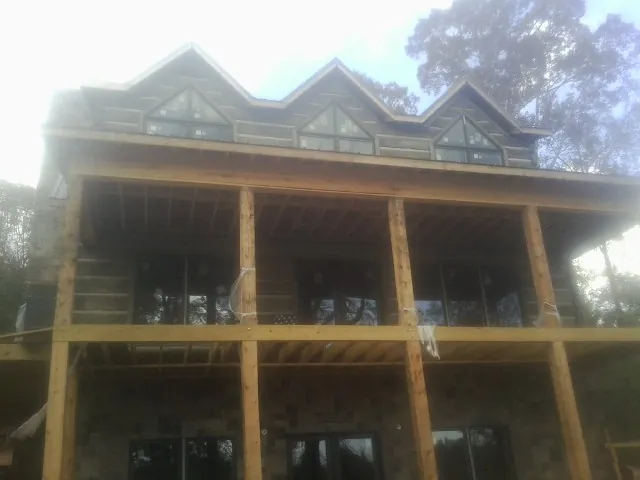 Dormers and porch framing on a large log home under construction — Roof Coating work by our crew in Crumpler