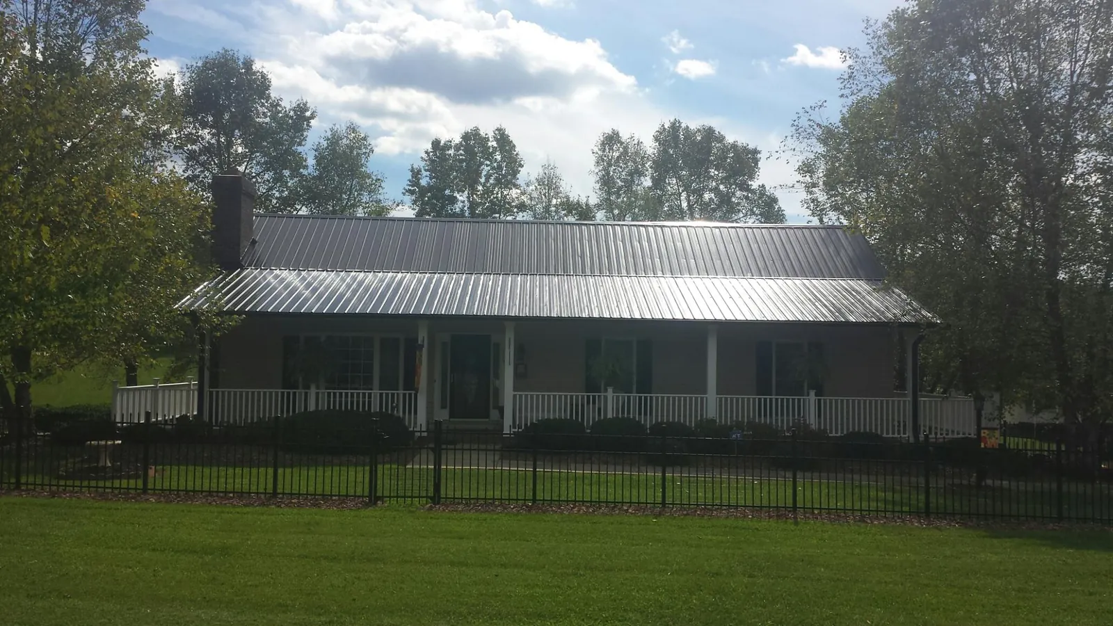 Gray metal roof on a brick ranch with a full width front porch — Gutter Guard Installation work by our crew in Crumpler